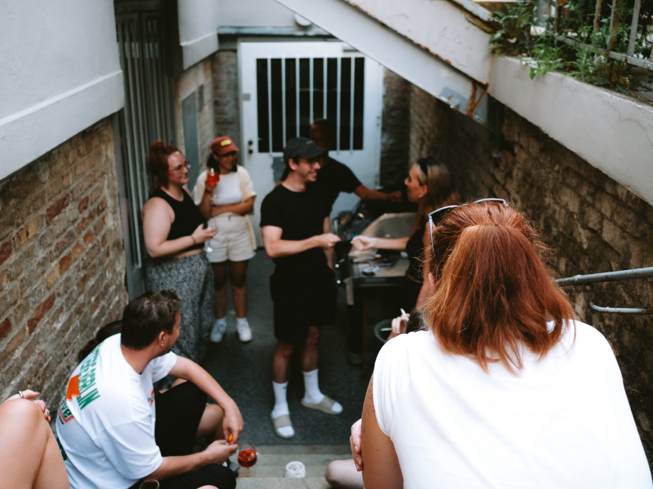 Modern lounge office with large windows streaming sunlight. The furnishings consist of green sofas and armchairs surrounded by numerous houseplants, creating a relaxing, natural atmosphere